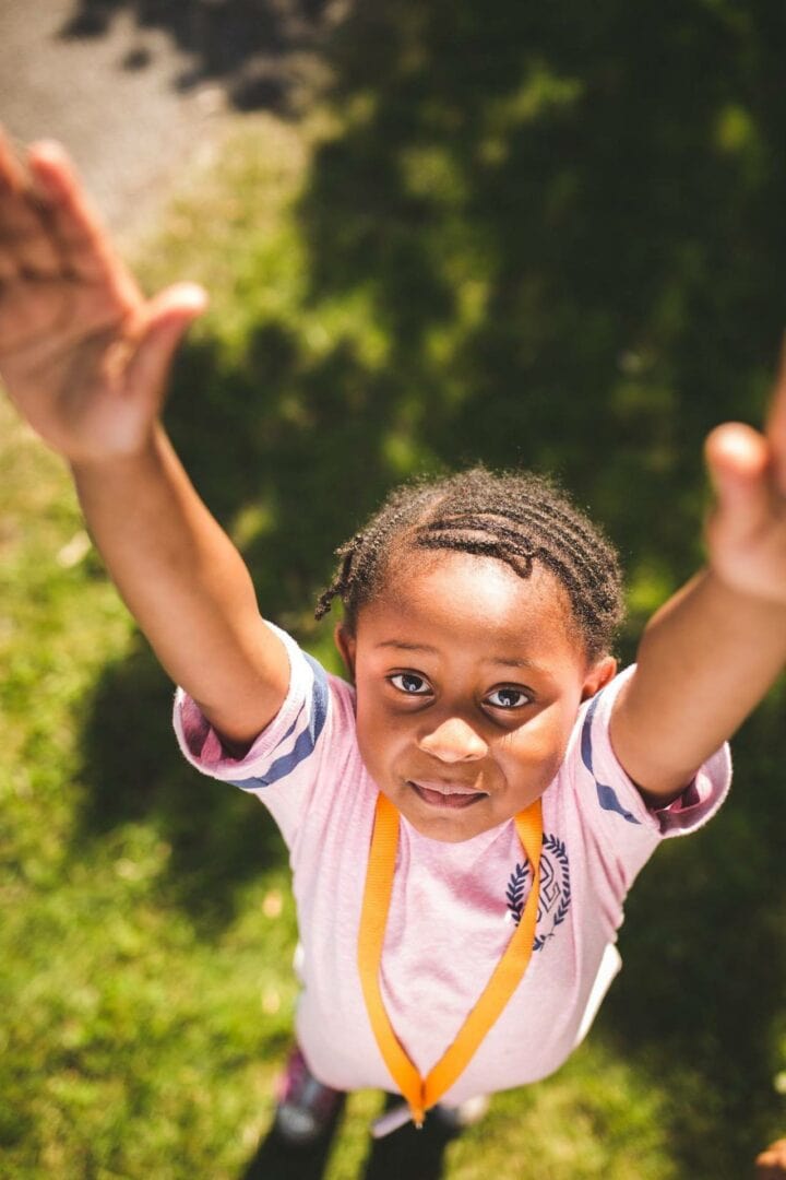 Girl standing on ground with hands stretched up